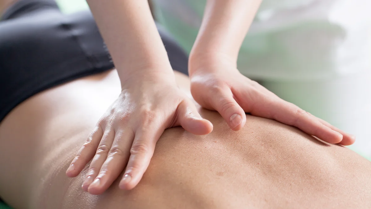 Hands-on soft-tissue massage technique applied to a patient's lower back during chiropractic treatment